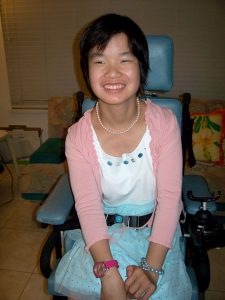 Young Asian woman in wheelchair smiling.