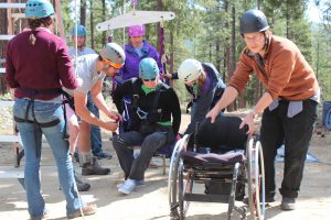 Grizzly Creek Ranch staffers help a youth in wheelchair get ready for the ropes course.